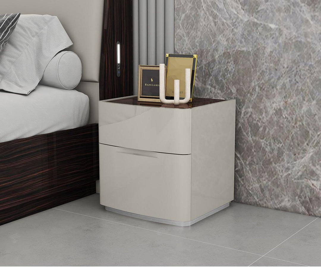 Beige nightstand with two drawers next to a bed in a bedroom setting.