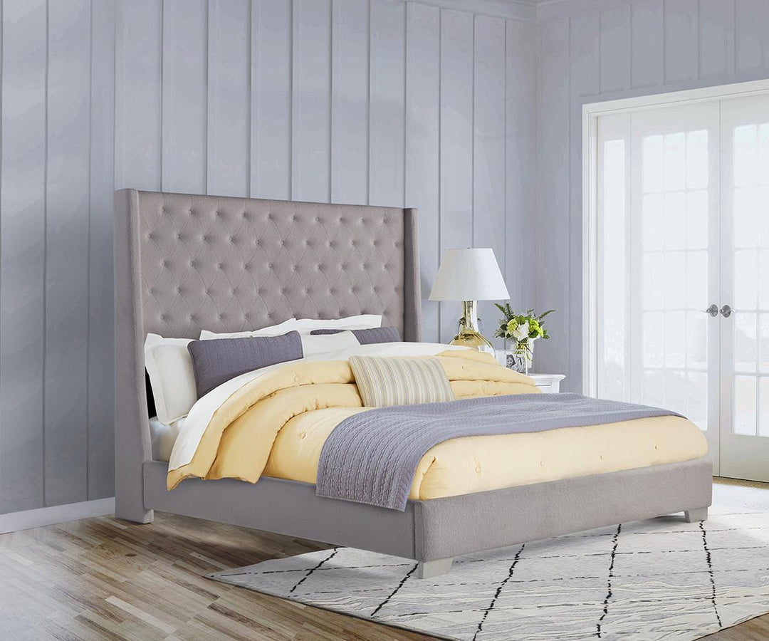 Gray upholstered bed with yellow bedding in a bedroom setting.