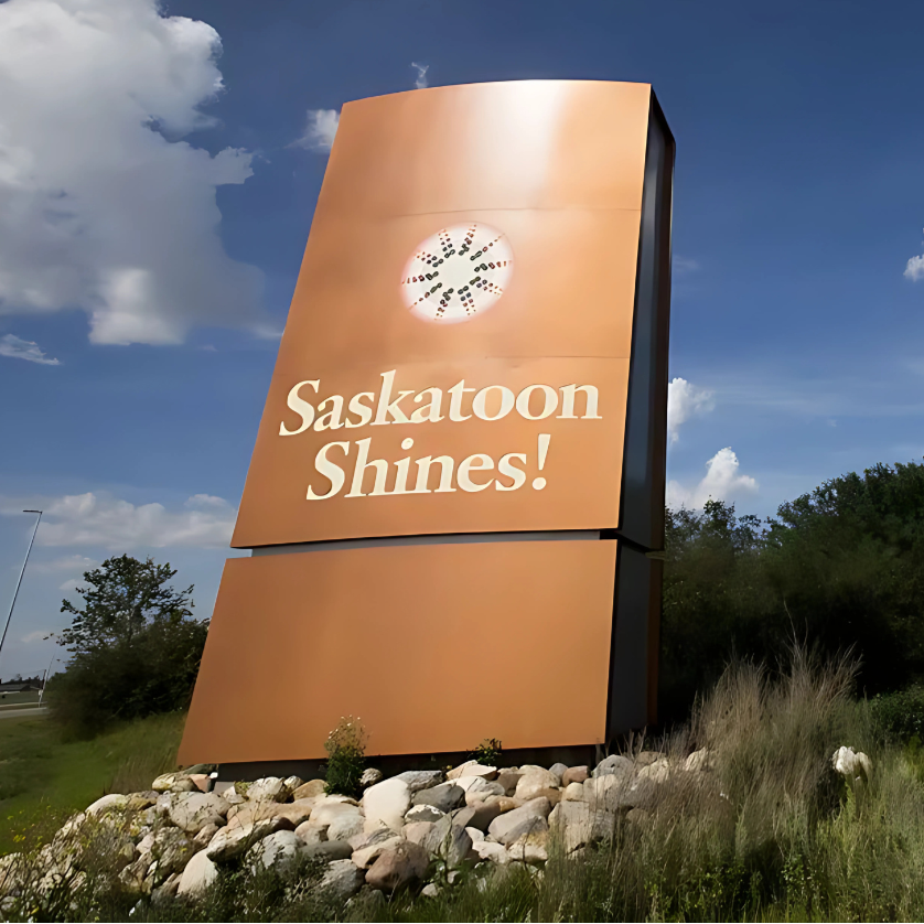 Large sign with 'Saskatoon Shines!' on a sunny day with blue sky and clouds.